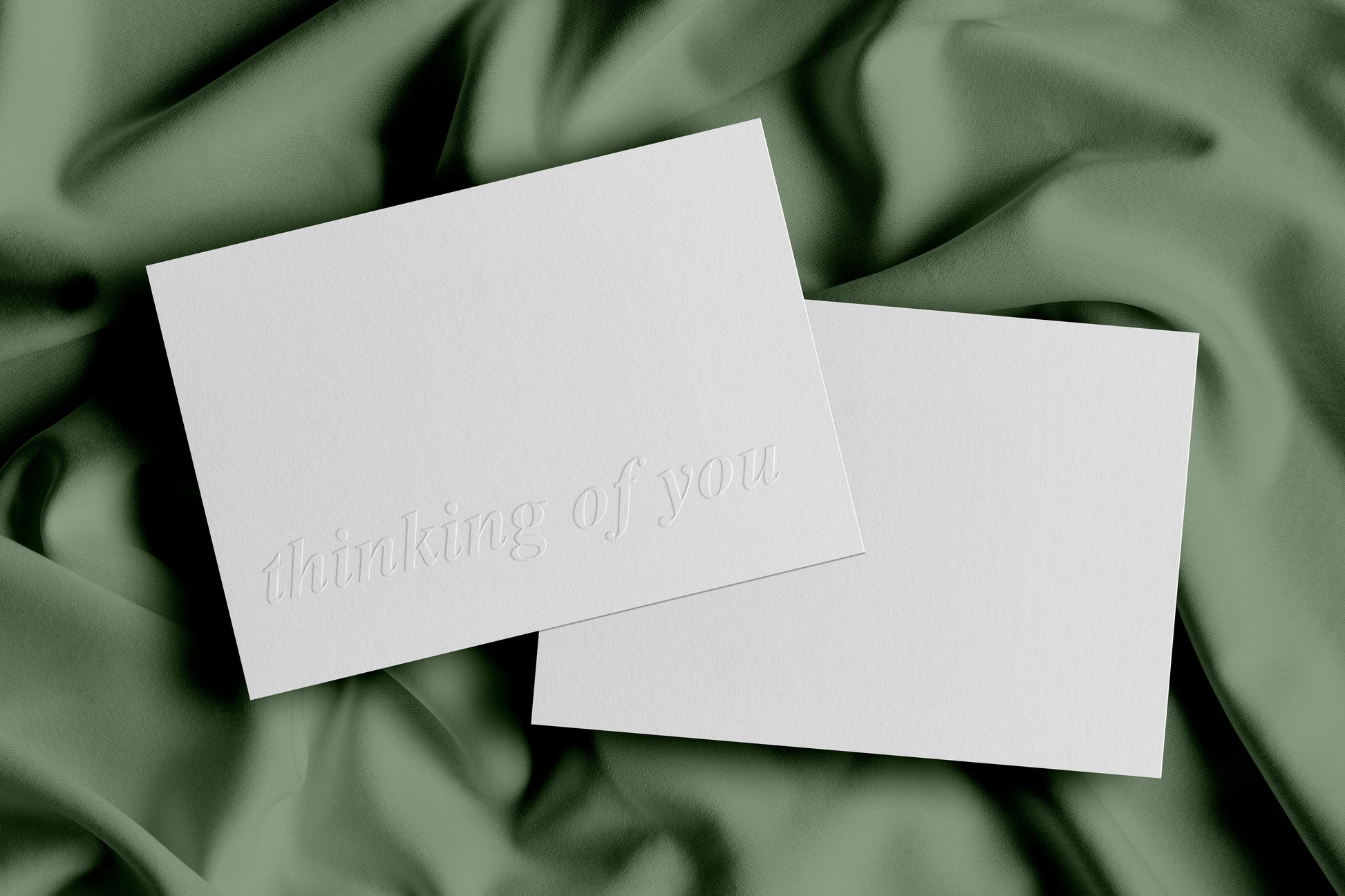 A plain white greeting card with 'thinking of you' embossed on the front